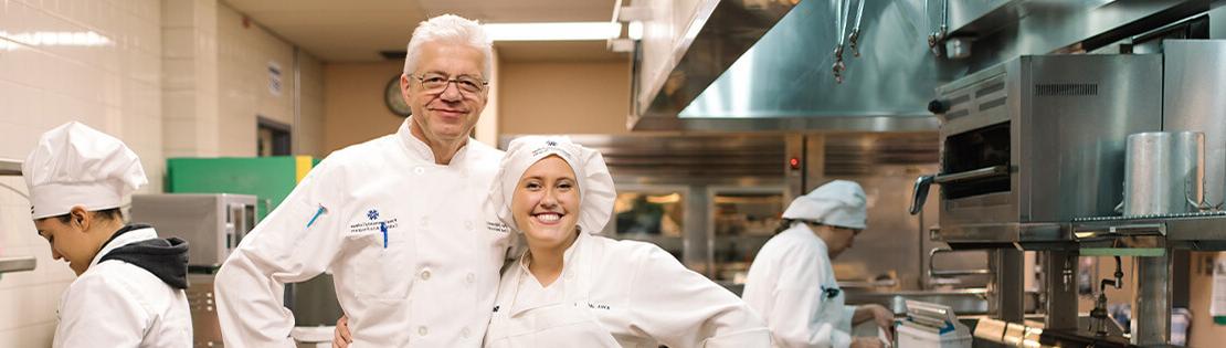 一位烹饪艺术学生和厨师微笑地站在皮马烹饪厨房里