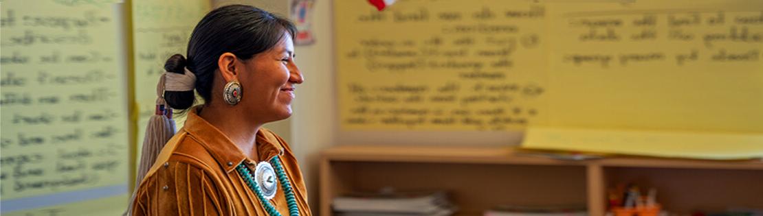 一位美国土著妇女微笑地站在皮马教室里